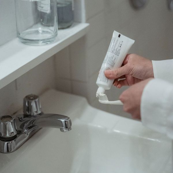 person putting toothpaste on a toothbrush