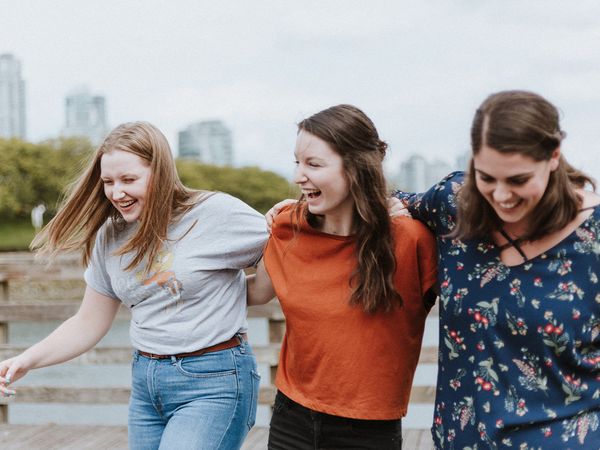 Three women laughing and walking outside.