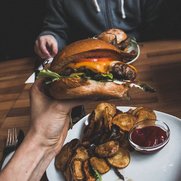 A person holding up a delicious-looking hamburger