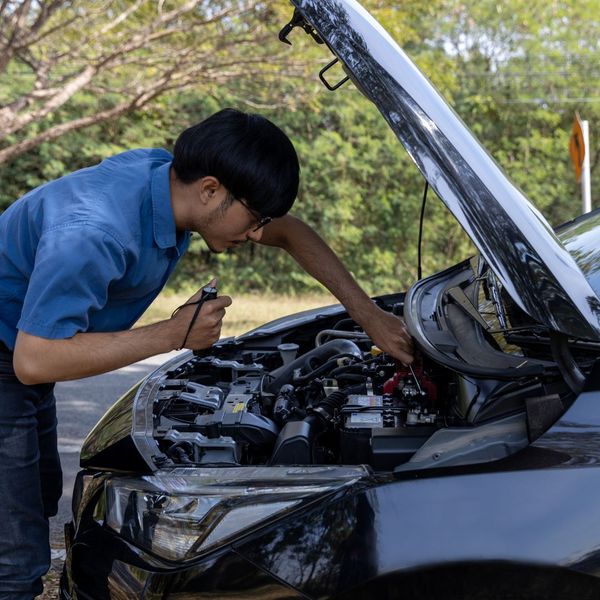 man looking at car with dead battery