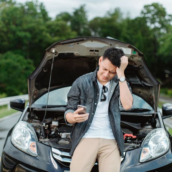 man leaning on broken down car