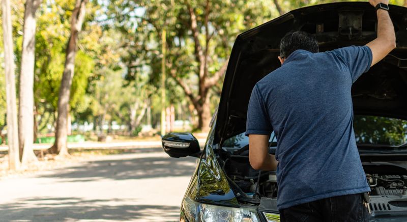 Person looking under the hood of his car