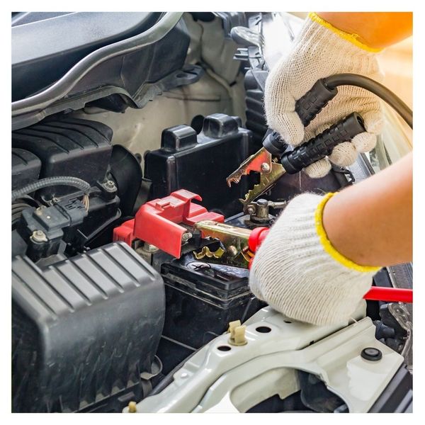 A mechanic jump starting a car