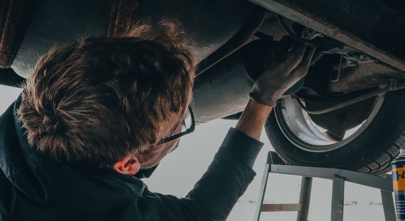 mechanic looking under car 