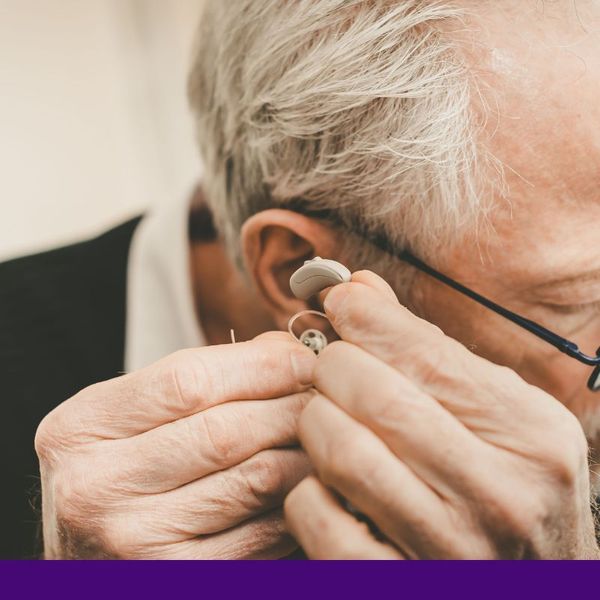 older man putting in hearing aid