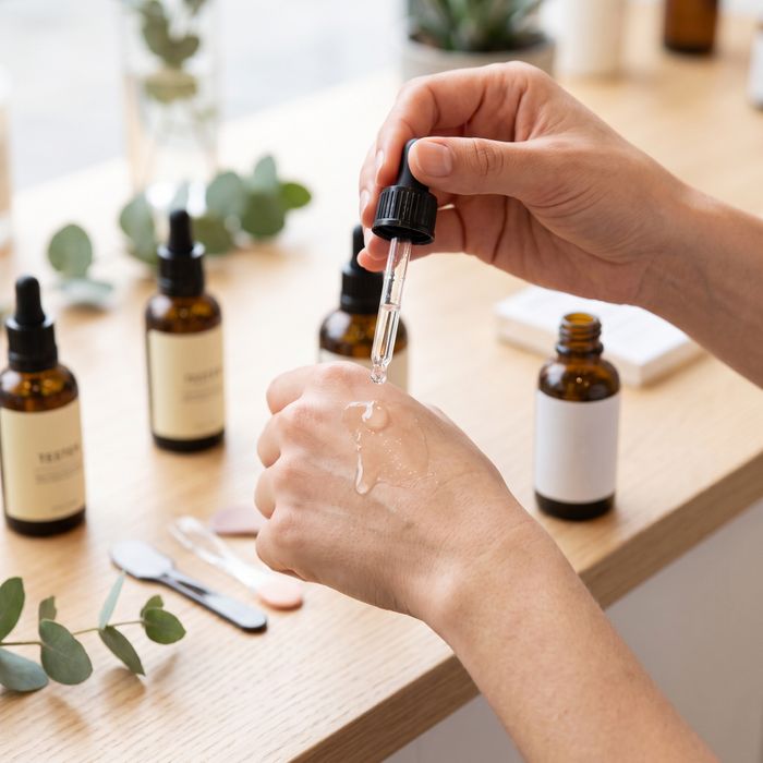 A close-up view of a person applying a sample serum from a dropper bottle onto their hand to test the texture.