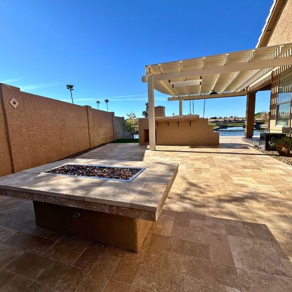 Custom attached lattice pergola over a luxury travertine paver patio with a built-in fire pit and outdoor kitchen in Northern Phoenix.