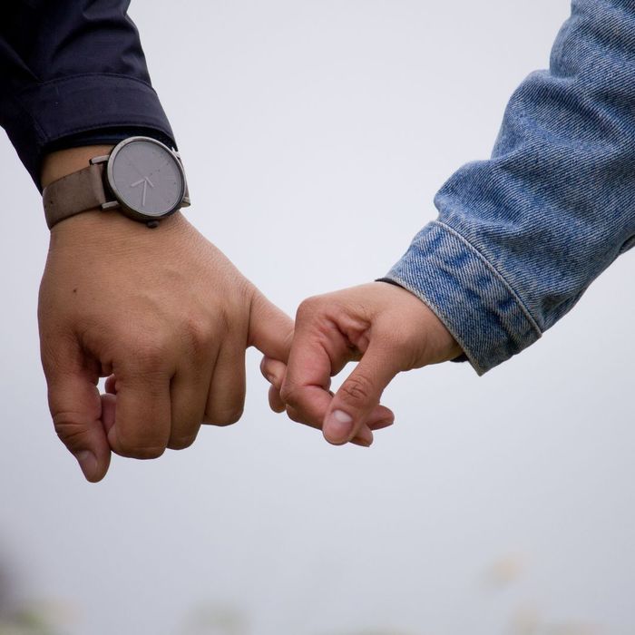 closeup of couple with interlocking pinky fingers