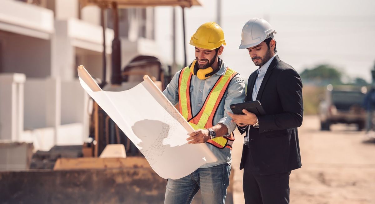 two male contractors looking at a blueprint. 