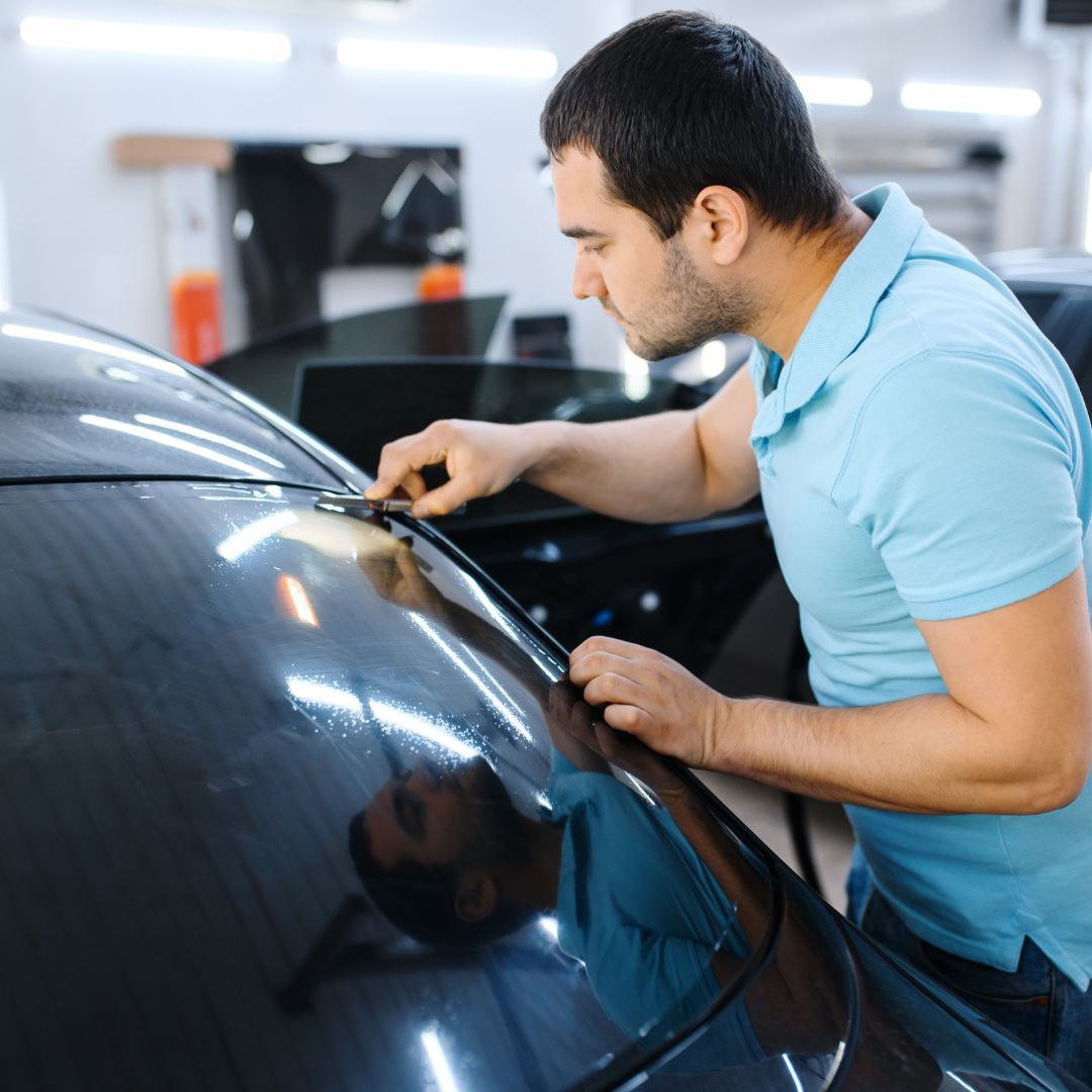 A man cuts and applies carbon window tinting