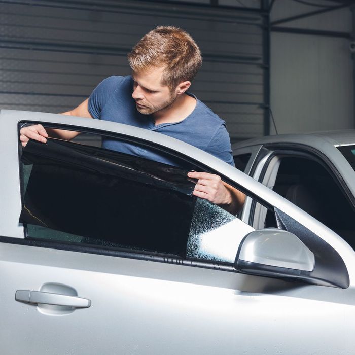 man putting auto tint on car