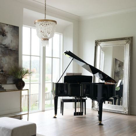 Elegant tier-layered capiz shell chandelier with gold trim suspended in a bright music room near a black grand piano.