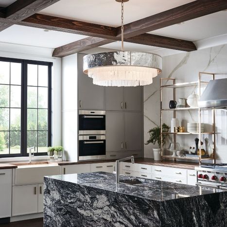 Large modern silver drum chandelier with cascading glass crystals hanging above a black marble kitchen island.