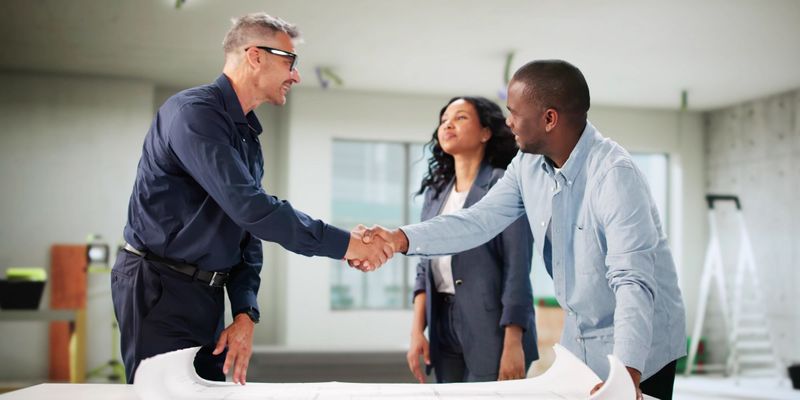remodeling specialist shaking hands with couple
