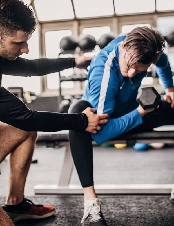 personal trainer assisting client with weights