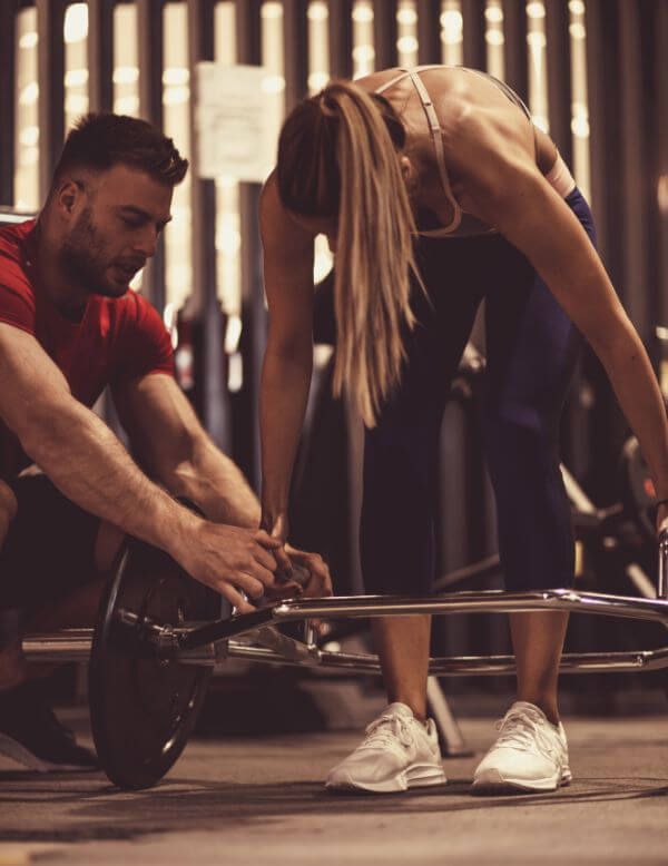 coach assisting client with barbell