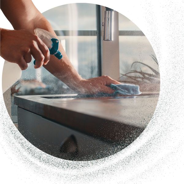 cleaning person uses spray bottle and towel to clean countertop