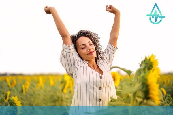 happy woman in field, eyes closed and arms outstretched