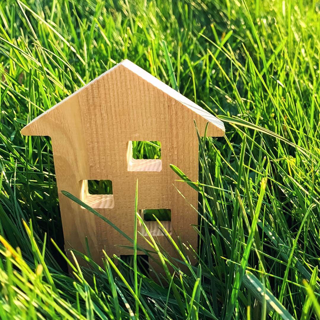 Miniature wooden house in green grass.  