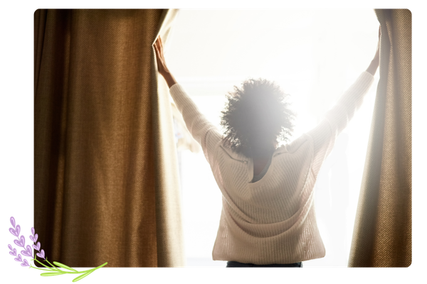 woman opening curtains to sunlight