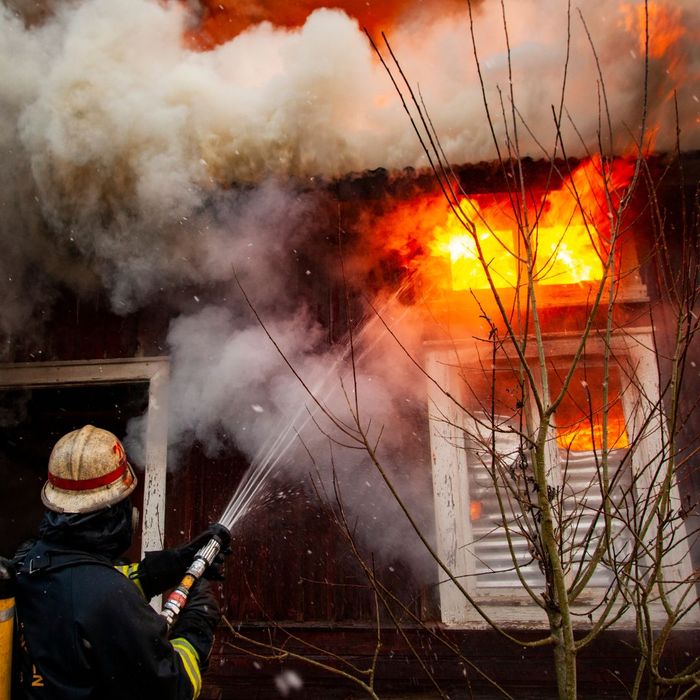 Firefighter hosing down house fire