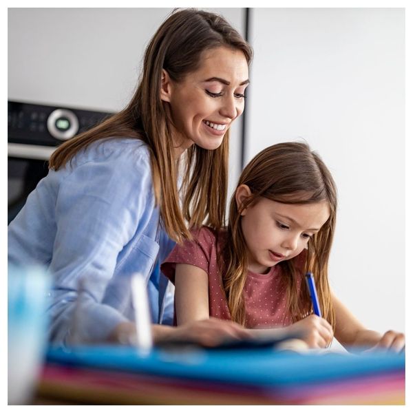 mom smiling helping daughter with homework