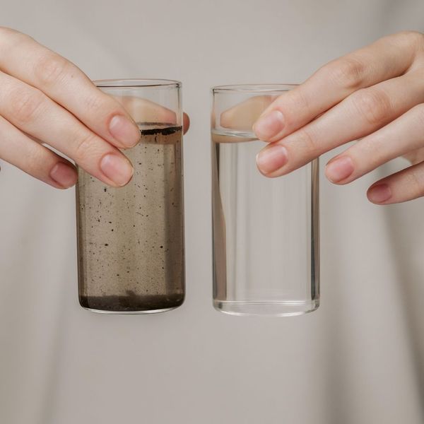 holding one glass of clean water next to a glass of water with contaminants holding one glass of clean water next to a glass of water with contaminants