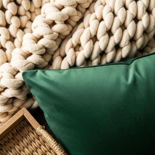 Close-up of layered home textiles including a chunky knit blanket and velvet fabric to show texture