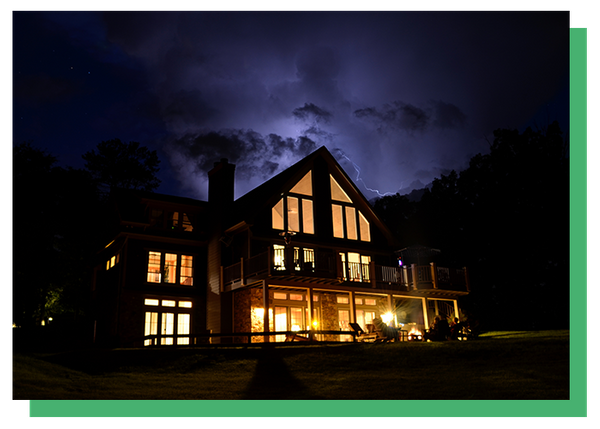 photo of a large house with lights up during a storm