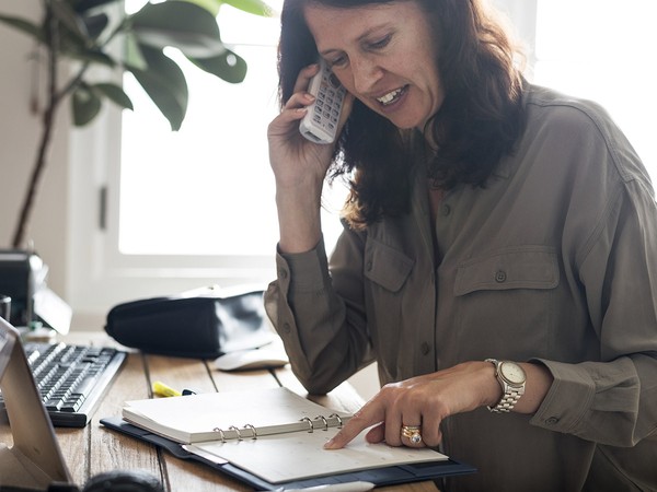 An image of a woman sitting in a home office talking on the phone.