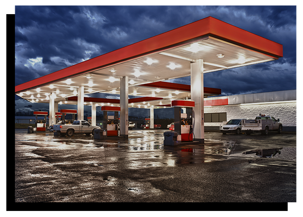 photo of gas station lit up in the middle of a storm