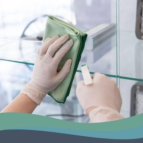 person using gloves cleaning spray and a cloth to clean surface