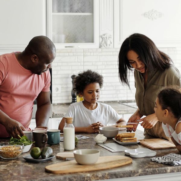 family of four cooking meal in kitchen