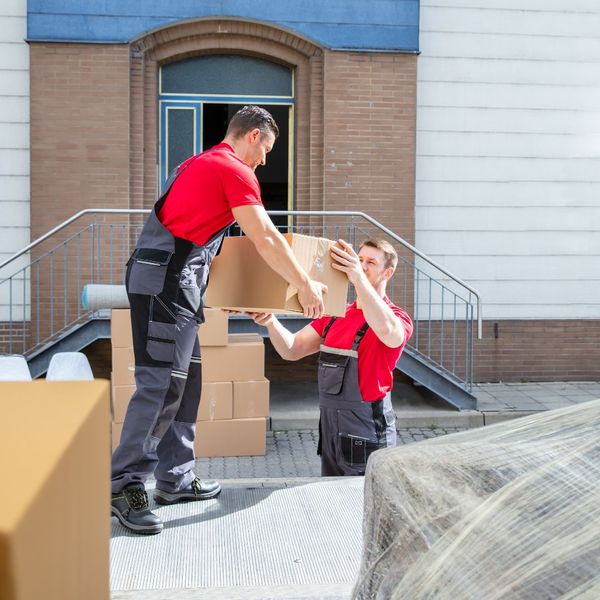 Male mover hands box to another male mover