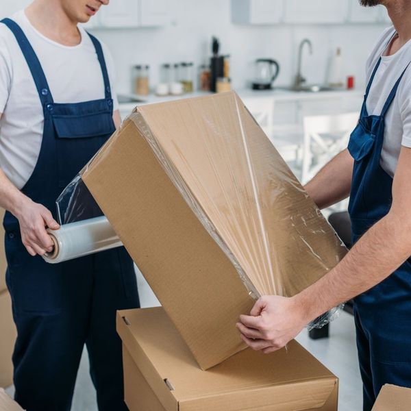 Two men wrap moving boxes