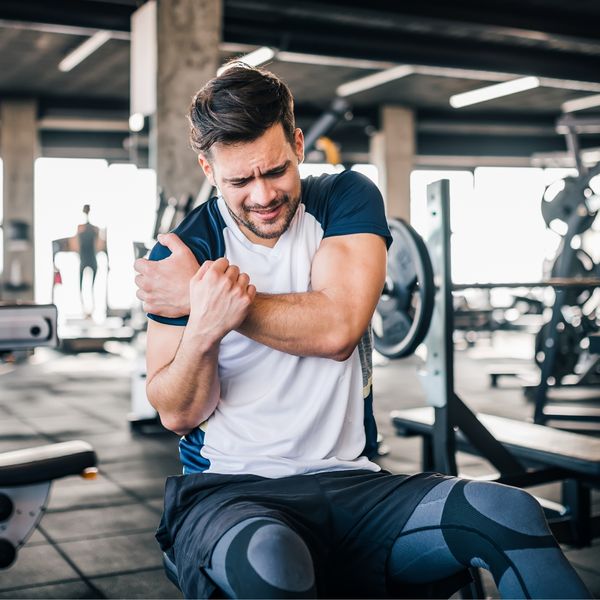 Man holding his shoulder in pain in a gym