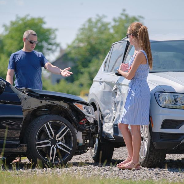 wide view of two people involved in a car accident arguing