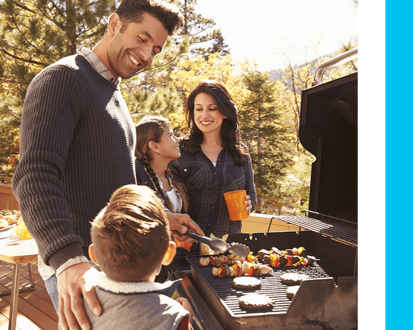 Image of a family grilling and enjoying being outside on their backyard deck