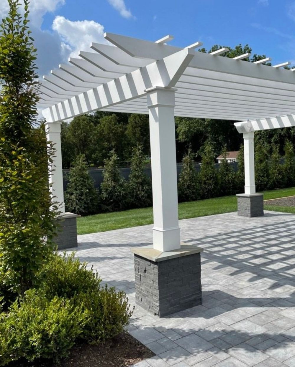 white pergola over stone patio