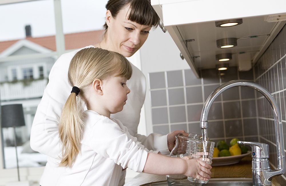 a mother and daughter getting a clean glass of water from the sink