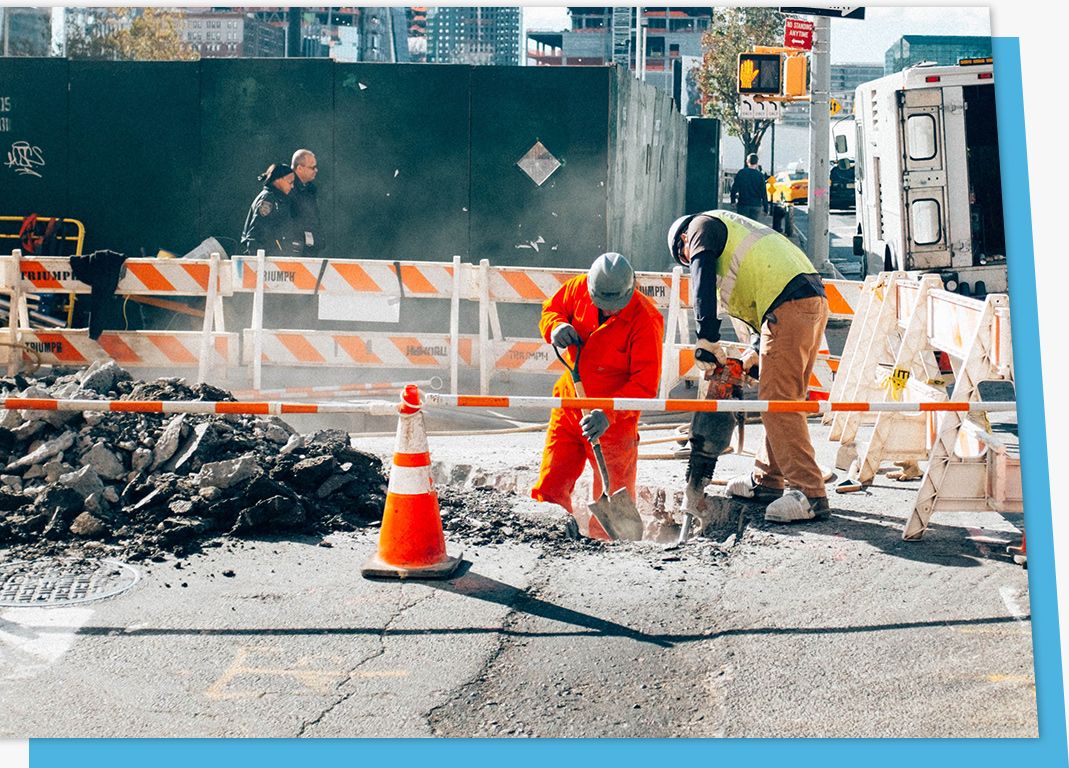 two workers using a jackhammer on nyc sidewalk