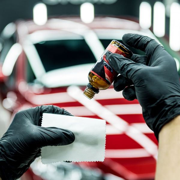 professional preparing a ceramic coating on a red vehicle