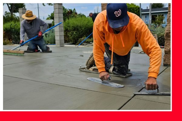 Two concrete workers kneeling, smoothing and finishing a freshly poured concrete surface with hand tools, wearing work gloves and hats. Two concrete workers kneeling, smoothing and finishing a freshly poured concrete surface with hand tools, wearing work gloves and hats.
