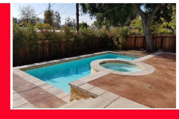 A modern backyard with a rectangular swimming pool and an adjoining circular hot tub, surrounded by stone coping and brown-toned stamped concrete. A modern backyard with a rectangular swimming pool and an adjoining circular hot tub, surrounded by stone coping and brown-toned stamped concrete.