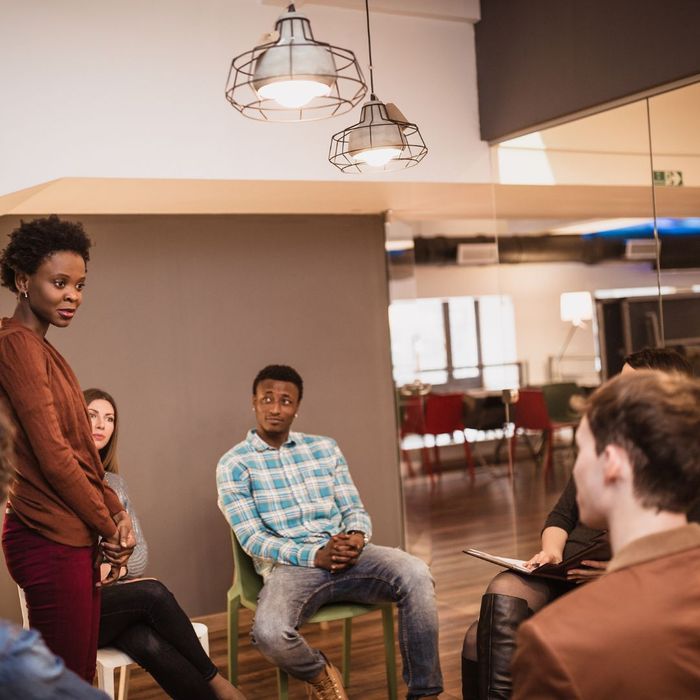 woman speaking a group of people seated in a circle