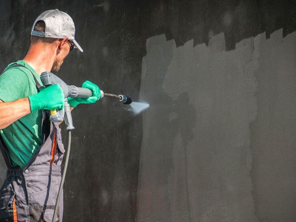 Image of a man power washing a wall.