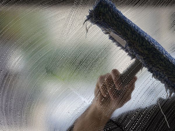 Image of a window cleaner using a squeegee on a window.