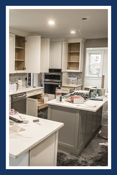 Messy home kitchen during remodeling with cabinet doors open.