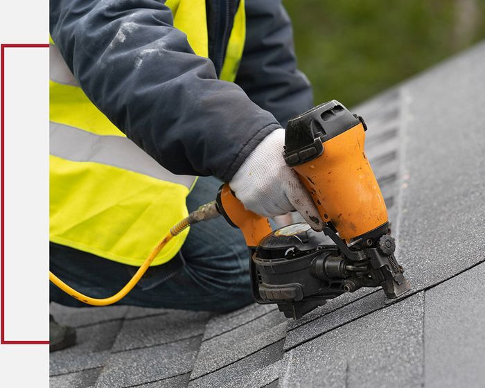 Roofer securing new shingles with nail gun