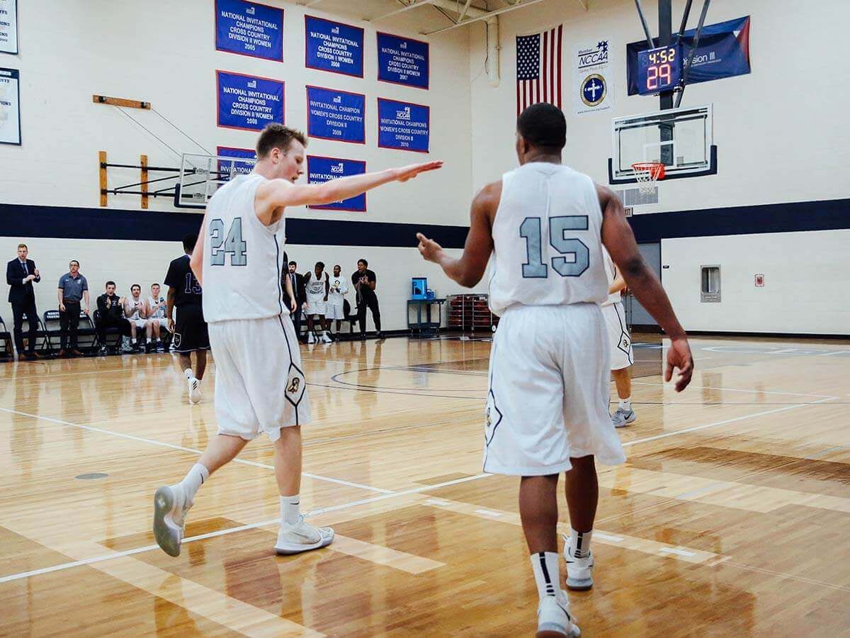 Two student basketball athletes high fiving.